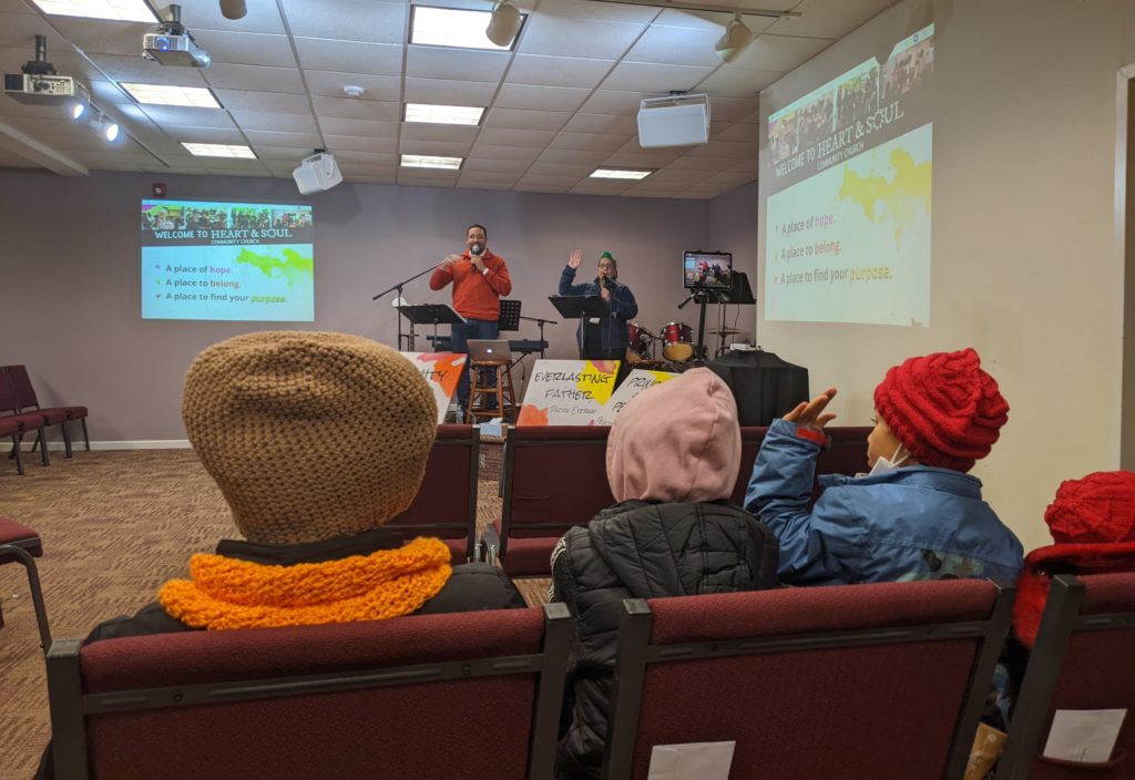 Sunday service with three small children in front row, one raising hand