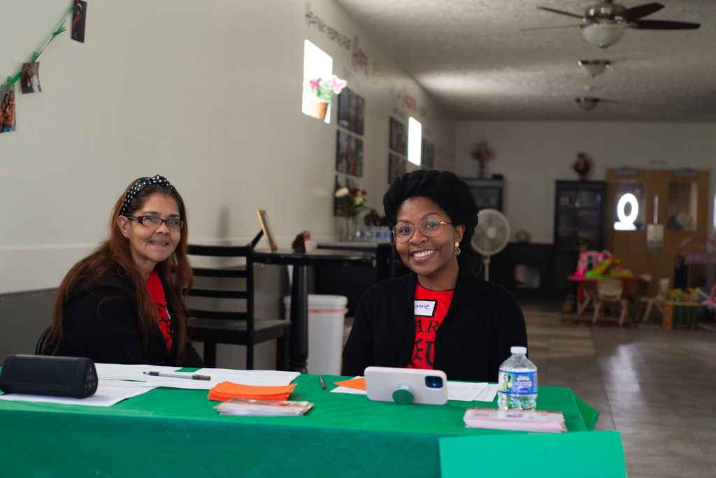 Two smiling ladies at front desk in church building